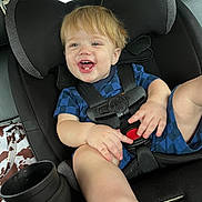 Berkley is registered to the contest to win money with this photo: toddler, child, car_seat, blue_clothing, smiling, happy, blond_hair, seatbelt, car_interior, cup_holder, sitting, portrait, baby, young_child, casual, fun, hands, feet, vehicle, seat