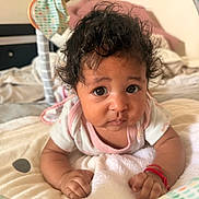 Ahzyna is registered to the contest to win money with this photo: baby, infant, curly_hair, blanket, bed, soft_toys, indoor, cute, portrait, child, young, person, pink_clothing, expression, face, hands, lying_down, closeup, cozy, warm