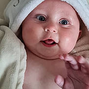 Maddison is registered to the contest to win money with this photo: baby, infant, face, hand, hooded_towel, towel, smile, blue_eyes, skin, cheeks, cute, child, young, expression, indoors, blanket, soft, warm, portrait, person
