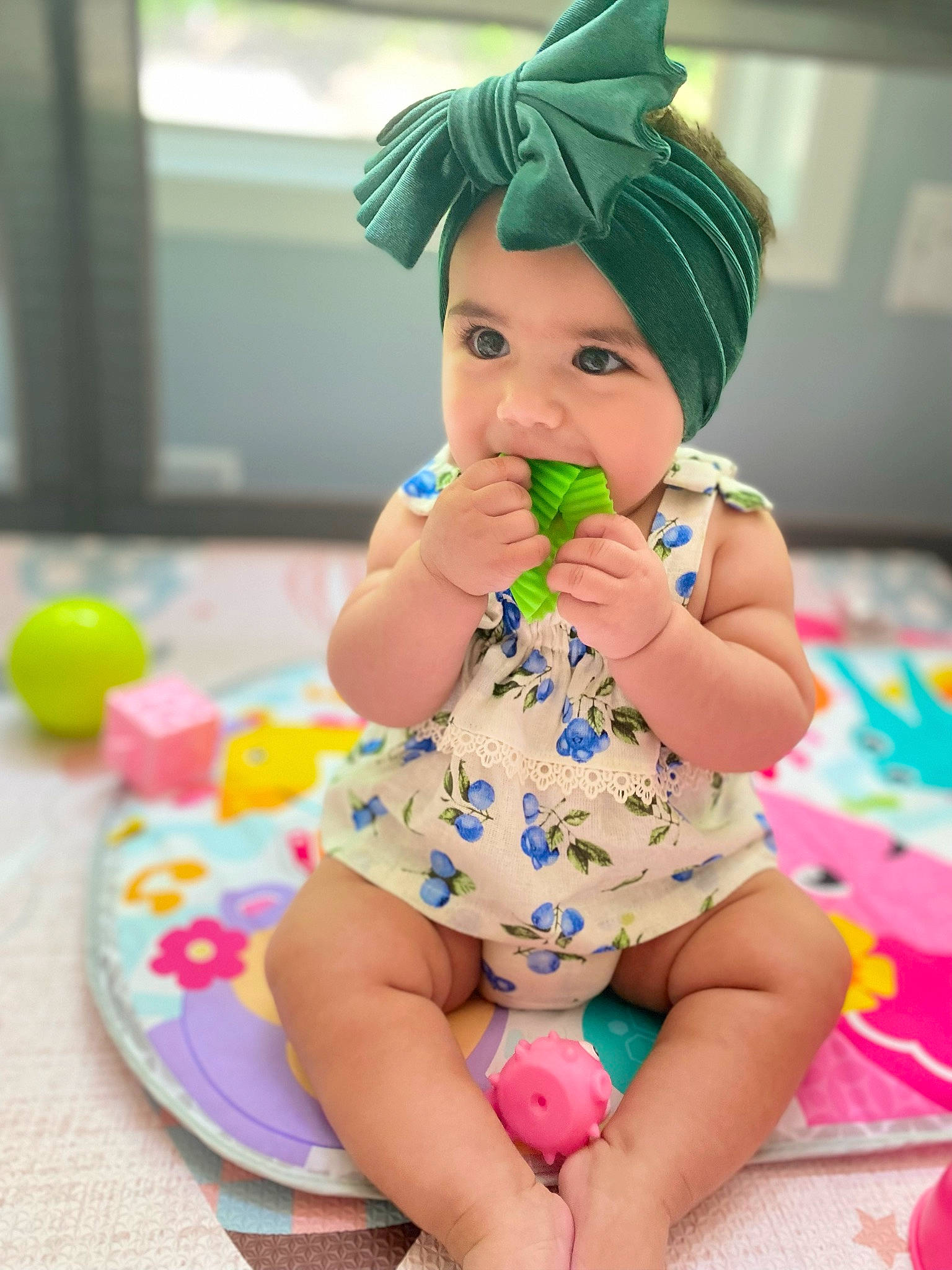 Rosalía is registered to the contest to win money with this photo: aqua, arm, baby, baby_toddler_clothing, cap, clothing, face, facial_expression, finger, green, hand, happy, hat, head, headwear, leg, person, pink, purple, skin