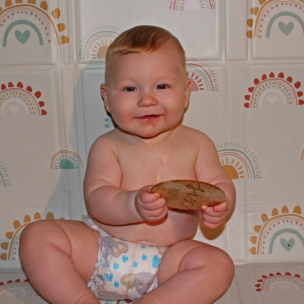 Zander joined the competition — help win amazing prizes! baby, background, child, chubby, cute, diaper, drool, face, hand, happy, indoors, infant, legs, playful, rainbow_pattern, sitting, skin, smile, toy, wooden_toy