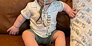 Zander is registered to the contest to win money with this photo: baby, child, pacifier, hat, bucket_hat, shirt, shorts, couch, pillow, indoor, furniture, portrait, sitting, cute, infant, hand, foot, face, expression, home