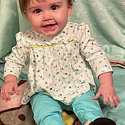 Elaina joined the competition — help win amazing prizes! baby, child, smiling, polka_dot, blue_bow, long_sleeve, pants, brown_shoes, blanket, sitting, indoors, cute, happy, face, hair, apparel, portrait, young_child, infant, cozy