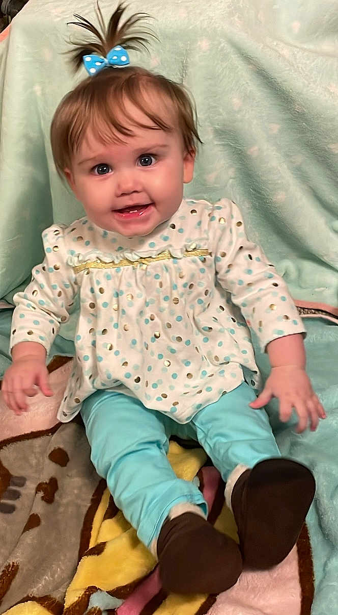 Elaina joined the competition — help win amazing prizes! baby, child, smiling, polka_dot, blue_bow, long_sleeve, pants, brown_shoes, blanket, sitting, indoors, cute, happy, face, hair, apparel, portrait, young_child, infant, cozy