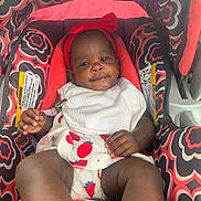 Dajana Miles is registered to the contest to win money with this photo: baby, infant, car_seat, headband, red_bow, patterned_fabric, strawberry_print, white_clothing, drool, smile, child, cute, seat, comfort, indoor, person, young_child, relaxing, portrait, baby_clothes