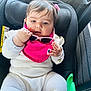 baby, car_seat, child, clothing, pink_bib, sunglasses, hair_clip, white_outfit, seatbelt, car_interior, cute, infant, portrait, child_seat, car, young_child, person, sitting, hand, face
