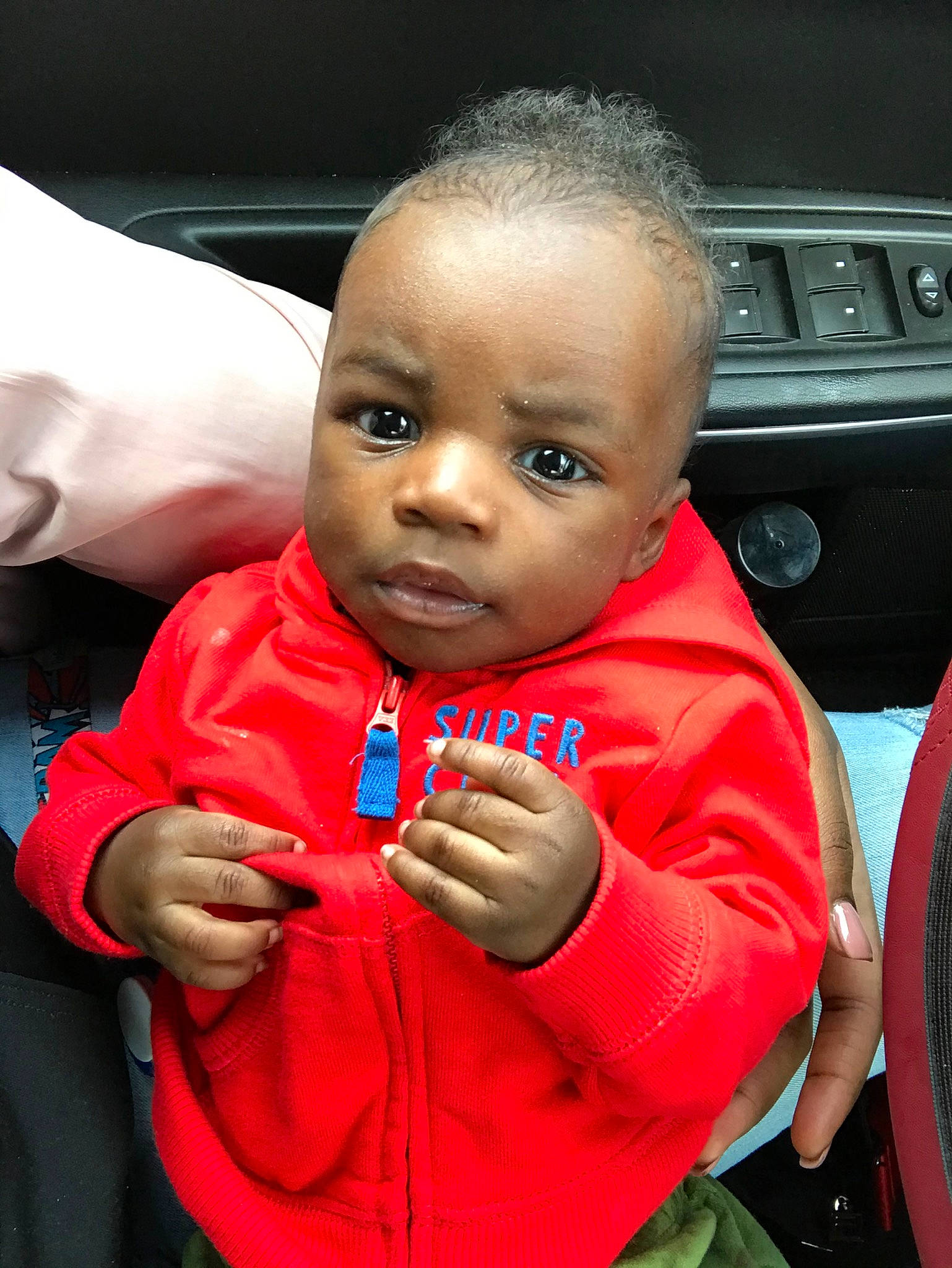 Tremaine is registered to the contest to win money with this photo: baby, car_seat, cheek, child, face, finger, forehead, gesture, head, lip, person, red, skin, smile, toddler