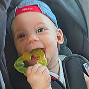 Malo a rejoint le concours — aidez-le/la à gagner de superbes lots ! baby, child, teething_toy, cap, car_seat, smiling, hand, face, infant, clothing, seatbelt, cute, young_child, happy, person, headwear, indoor, closeup, baby_toy, chewing