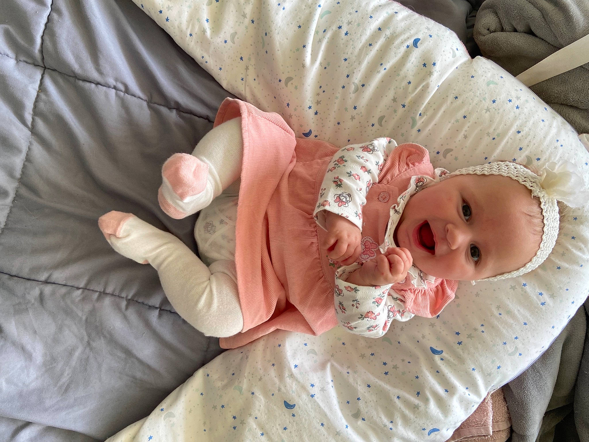 Eloise participe au concours pour gagner de l'argent avec cette photo : arm, baby, baby_products, baby_safety, baby_toddler_clothing, child, comfort, dress, eye, finger, hand, head, headgear, human_body, iris, linens, person, pink, skin, sleeve