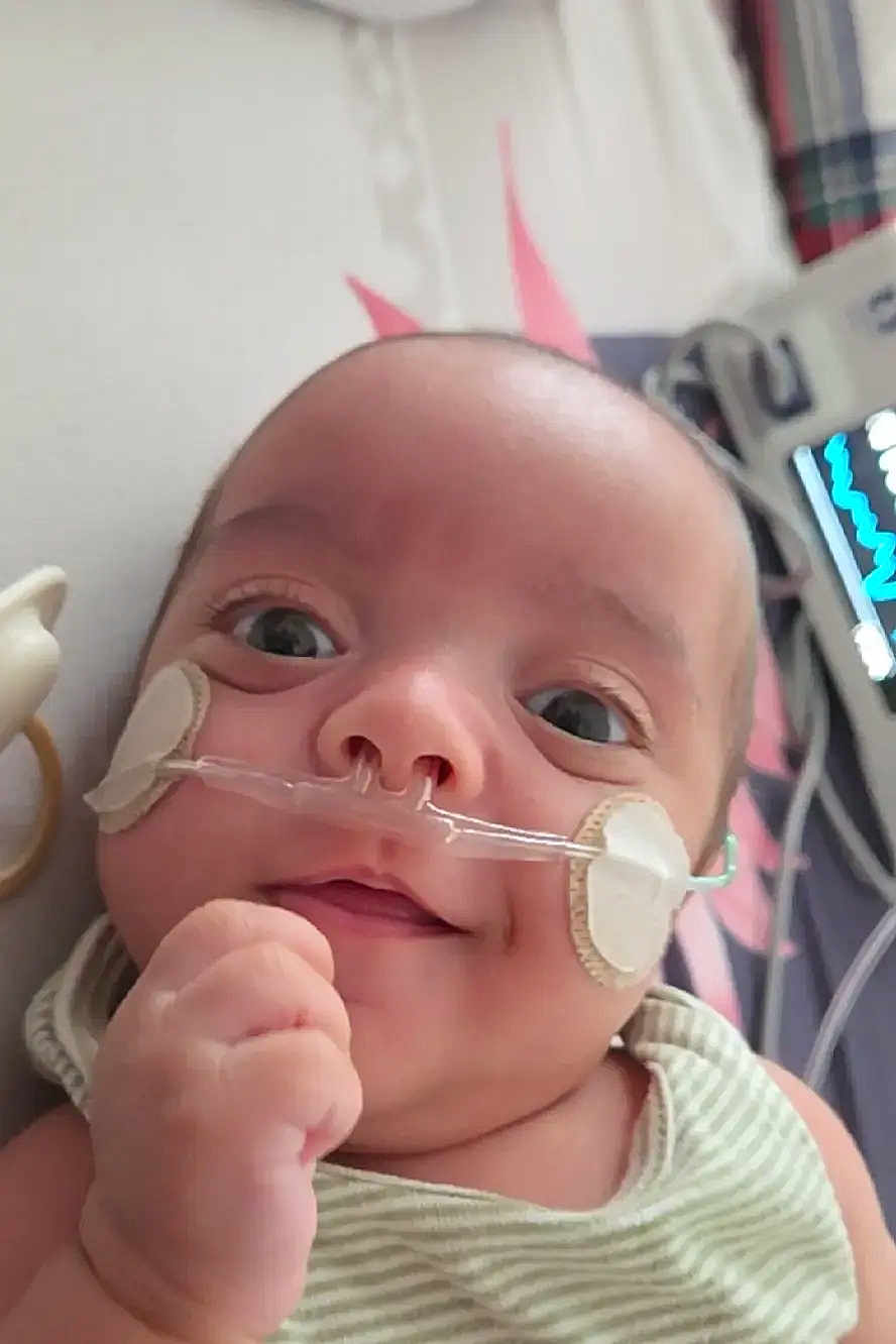 Matheo D joined the competition — help win amazing prizes! baby, infant, face, nasal_cannula, medical_patch, hospital, medical_equipment, striped_clothing, hand, lying_down, close_up, healthcare, child, person, cute, expression, indoors, monitor, smile, young