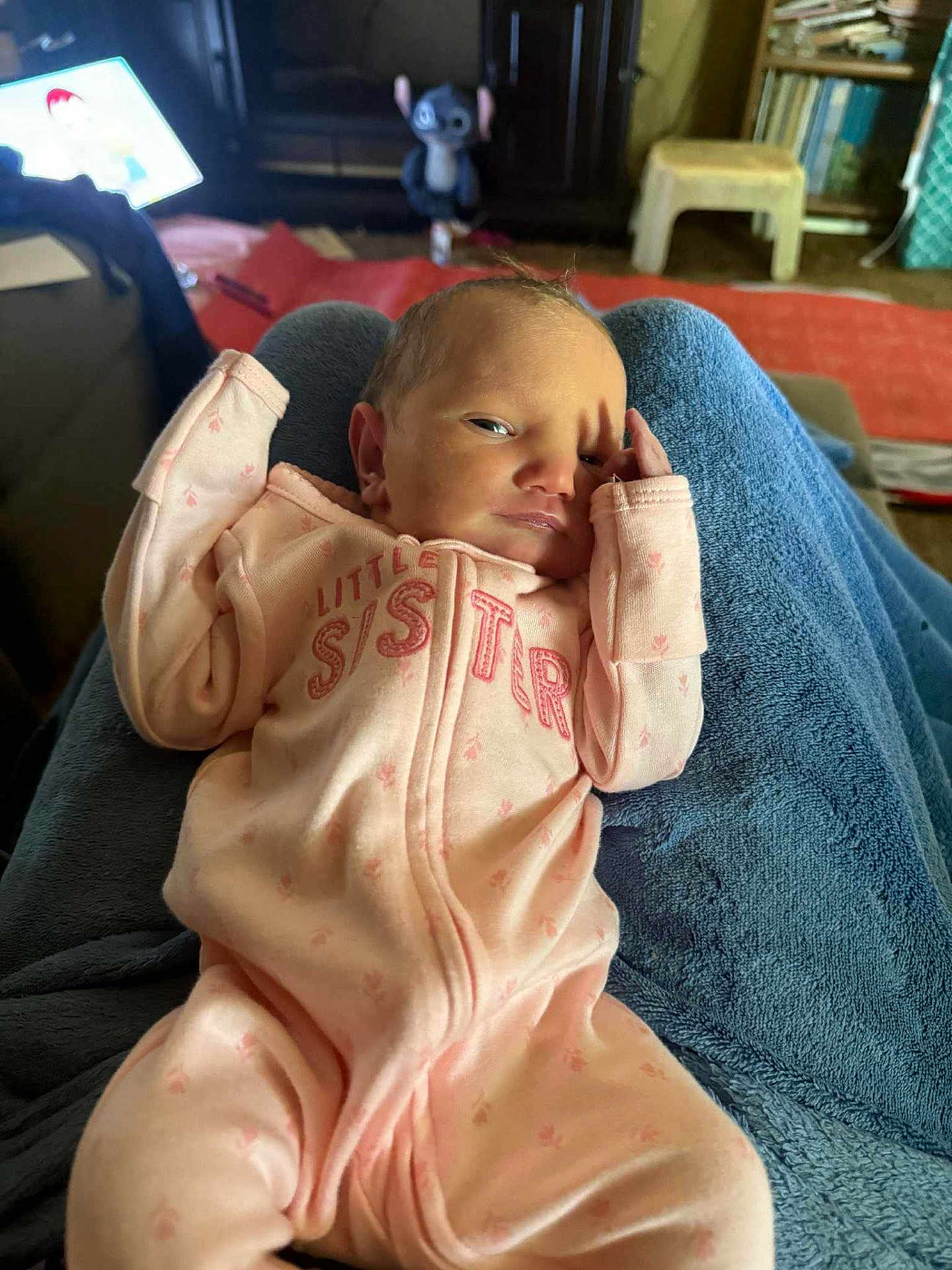 Alana is registered to the contest to win money with this photo: baby, newborn, infant, pink_sleeper, little_sister, blanket, indoor, plush_toy, blue_blanket, furniture, curious, face, person, resting, cozy, hand, child, soft_lighting, casual, relaxed