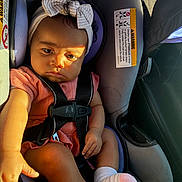 Mahlani is registered to the contest to win money with this photo: baby, baby_hand, bow, car, car_interior, car_seat, child, child_safety, cute, headband, infant, pink_outfit, portrait, seat, seatbelt, serious_face, socks, straps, sunlight, young_child