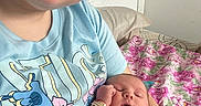 Oakleigh is registered to the contest to win money with this photo: baby, sleeping, woman, glasses, holding, onesie, winnie_the_pooh, floral_blanket, indoor, smiling, portrait, person, cute, cozy, child, bedroom, resting, family, casual, happy