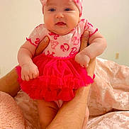 Maria is registered to the contest to win money with this photo: baby, child, infant, pink_clothing, headband, bow, tutu, arms, hands, blanket, soft_texture, indoor, person, cute, adorable, smile, skin, face, legs, sock