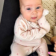 Lyla Jo is registered to the contest to win money with this photo: baby, infant, onesie, pink, hearts, face, blue_eyes, cushion, blanket, hand, nail_polish, indoor, portrait, cute, child, person, soft_lighting, cozy, seated, expression