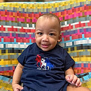 Zyaire is registered to the contest to win money with this photo: baby, child, smiling, face, person, clothing, toddler, indoor, patterned_fabric, colorful, seat, cute, happy, portrait, apparel, sitting, one_piece, young_child, infant, casual