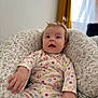 Denise participe au concours pour gagner de l'argent avec cette photo : baby, child, infant, pigtails, floral_pattern, cushion, onesie, reaching_hand, indoor, soft_lighting, portrait, cute, comfortable, seated, expression, person, young_child, home, cozy, colorful_clothing