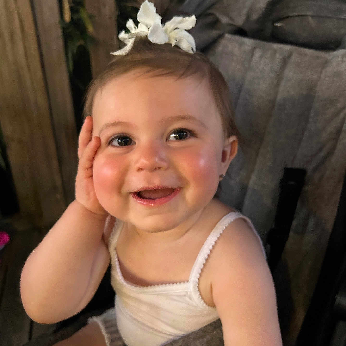Lúccia participe au concours pour gagner de l'argent avec cette photo : arm, baby, cheeks, child, cute, eyebrows, face, flower, happy, headband, infant, outdoor, person, portrait, seatbelt, skin, smiling, stroller, white_clothing, wooden_background