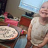 Echo is registered to the contest to win money with this photo: toddler, child, birthday_cake, cake, smiling, indoor, toy, floor, window, cat, furniture, celebration, candle, homemade, clothing, happy, person, room, flooring, party