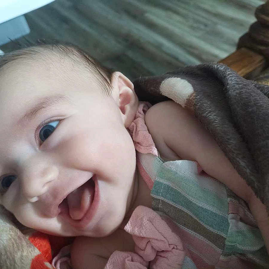 Hazel joined the competition — help win amazing prizes! baby, smiling, blanket, child, happy, face, infant, cute, portrait, indoors, cozy, clothing, person, head, skin, bright_eyes, expression, closeup, newborn, toddler