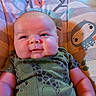 baby, infant, child, smile, seated, baby_chair, green_clothing, animal_print, indoor, couch, face, head, arm, furniture, comfort, cute, plush, young_child, portrait, happy