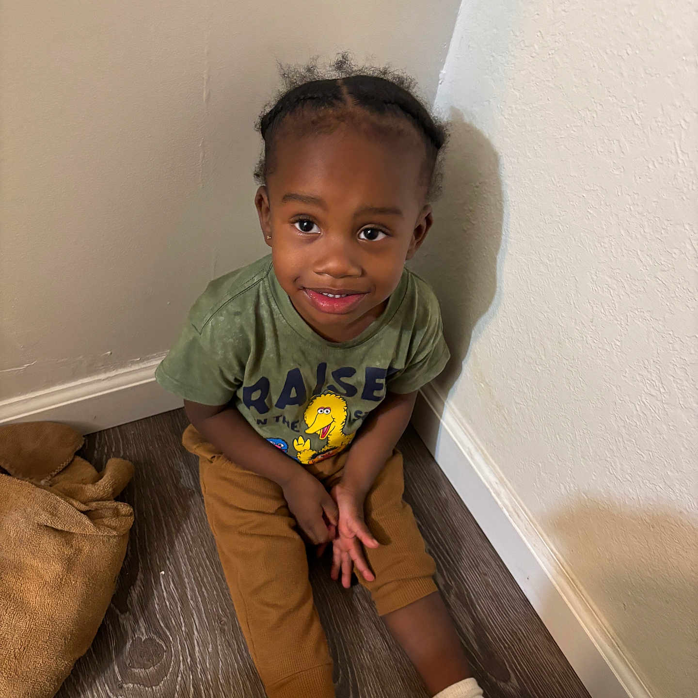 Kordae joined the competition — help win amazing prizes! child, smiling, sitting, floor, corner, green_shirt, brown_pants, socks, teddy_bear, wooden_floor, wall, indoors, cute, happy, portrait, person, casual_clothing, young_child, hair, eyebrows