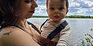 Meï participe au concours pour gagner de l'argent avec cette photo : baby, adult, woman, child, tattoo, necklace, headband, outdoor, lake, water, cloud, sky, nature, person, holding, striped_clothing, brown, greenery, portrait, closeup