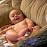 Kai joined the competition — help win amazing prizes! baby, infant, child, smiling, happy, portrait, sitting, couch, cushions, blanket, remote_control, living_room, indoor, cozy, face, eyes, hands, feet, barefoot, photography