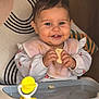 baby, bib, high_chair, smile, food, snack, toy, indoor, child, happy, face, person, clothing, seat, furniture, cute, messy, hands, table, home