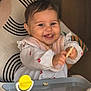 Giorgia participe au concours pour gagner de l'argent avec cette photo : baby, child, smiling, high_chair, food, toy, happy, face, hands, clothing, bib, indoor, seat, table, crumbs, person, cute, infant, playful, feeding
