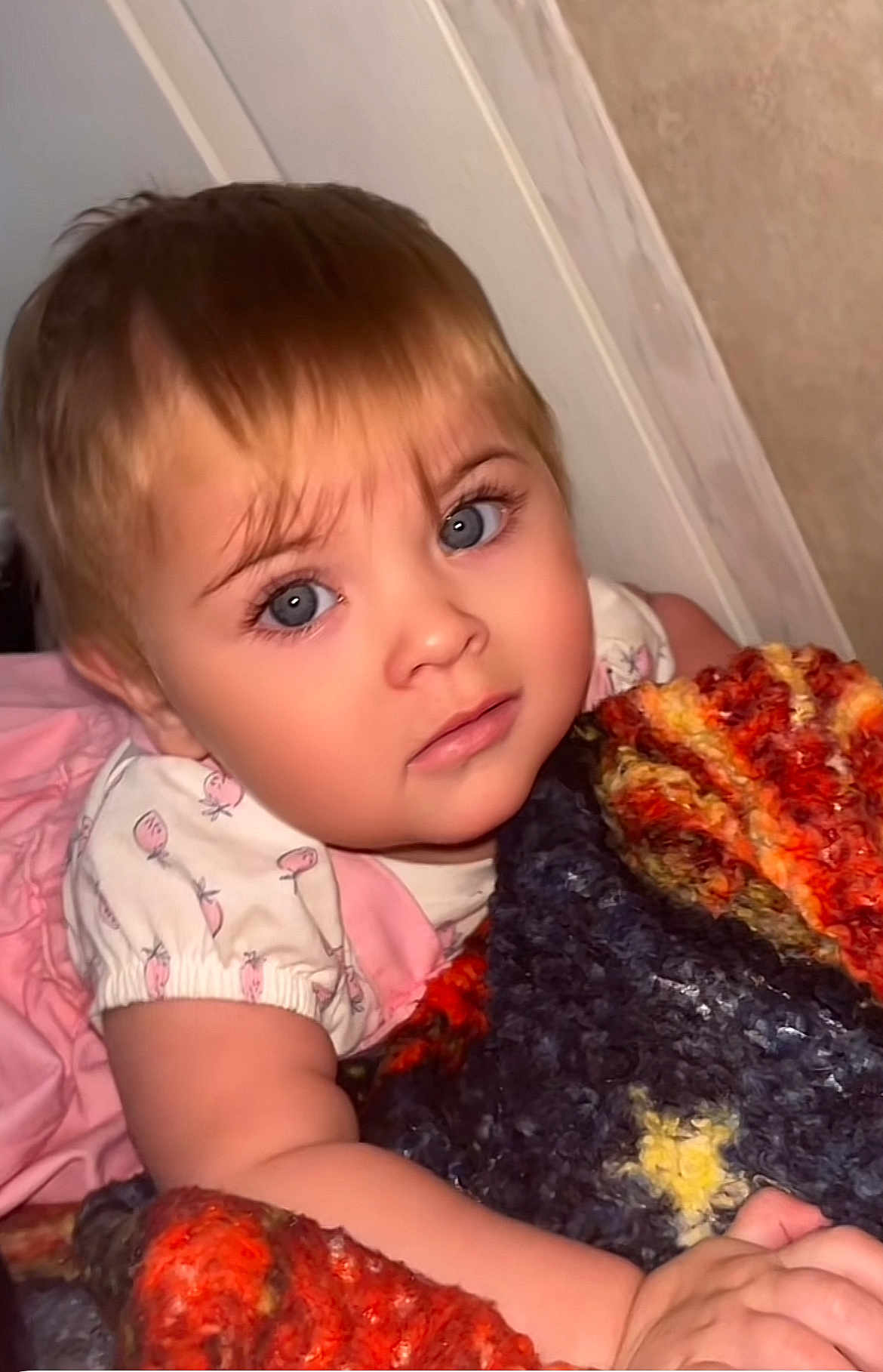 Valerie joined the competition — help win amazing prizes! toddler, child, blanket, blue_eyes, curly_hair, knitted_blanket, indoor, portrait, cute, expression, face, person, young_child, hand, pink_clothing, soft_lighting, close_up, baby, wearing, sleeves