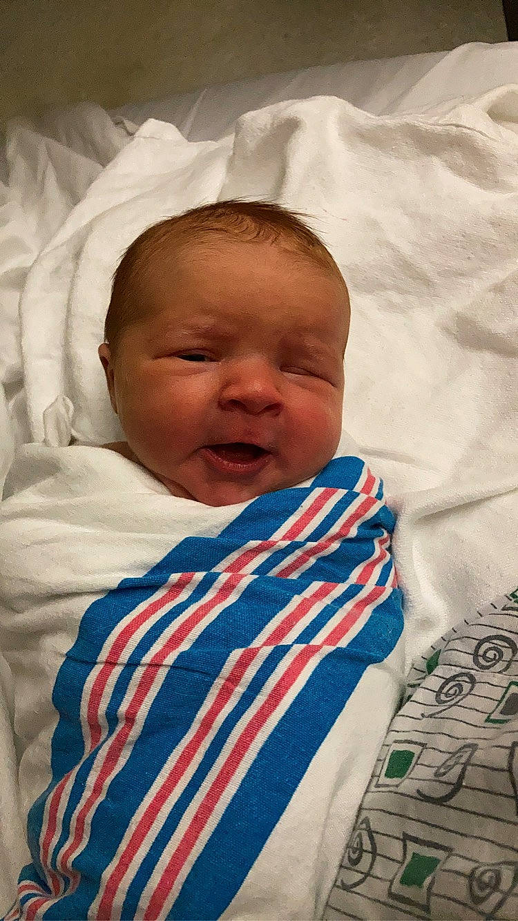 Everest is registered to the contest to win money with this photo: baby, baby_toddler_clothing, bedding, cheek, child, chin, comfort, eye, eyebrow, face, happy, linens, mammal, mouth, nose, person, skin, sleeve, smile, textile