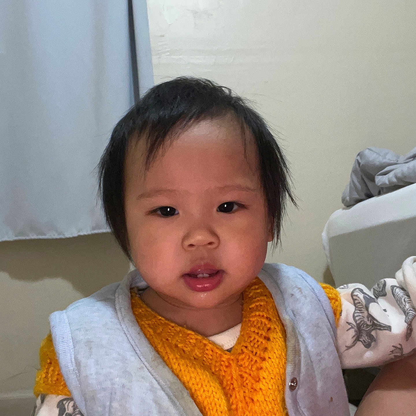 Tiffany is registered to the contest to win money with this photo: baby, casual, child, clothing, curtain, face, gray_jacket, indoor, looking_at_camera, neutral_expression, patterned_clothing, person, portrait, short_hair, skin, sleeves, toddler, wall, yellow_vest, young_child