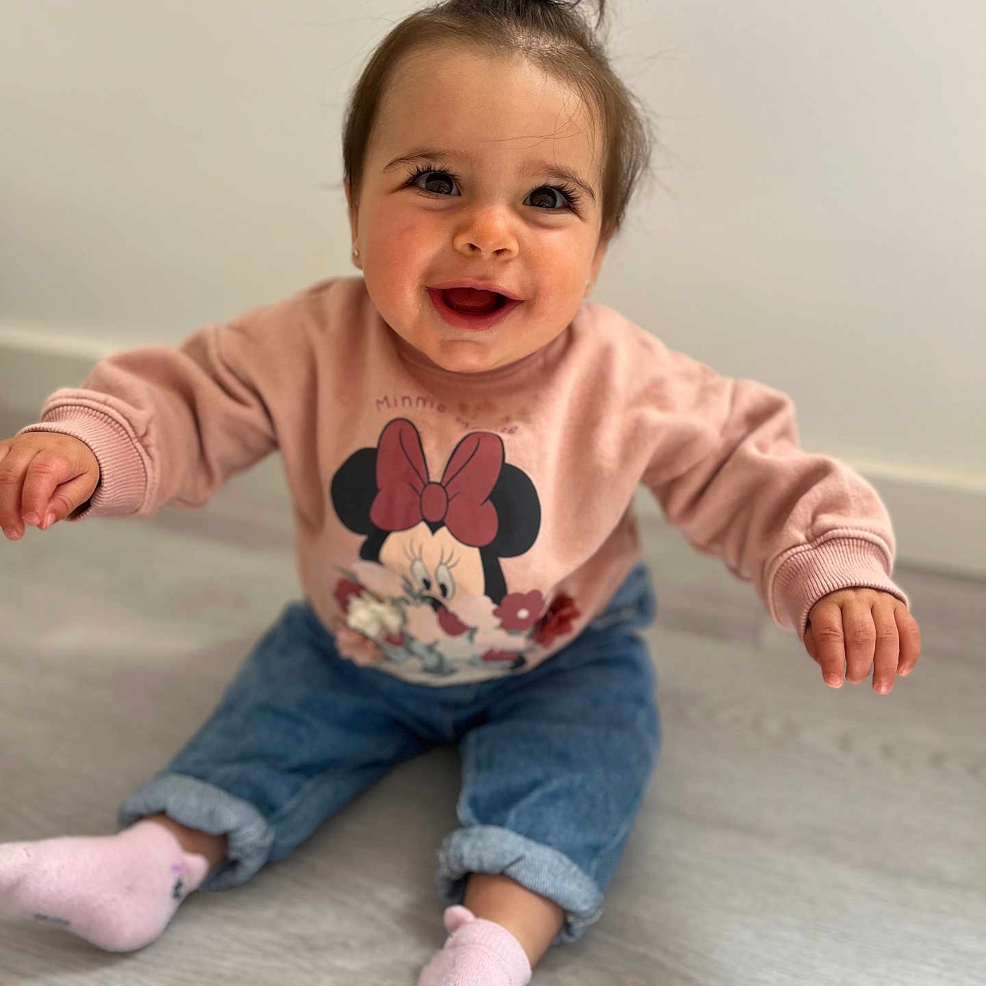 Louna a rejoint le concours — aidez-le/la à gagner de superbes lots ! baby, blue, casual_clothing, child, cute, floor, hair_tie, happy, indoor, jeans, light_background, minnie_mouse, person, pink, portrait, sitting, smiling, socks, sweatshirt, young_child