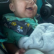 Armand is registered to the contest to win money with this photo: baby, child, infant, smiling, happy, portrait, car_seat, car, travel, blanket, fluffy_blanket, green_clothing, floral_pattern, safety_harness, seated, indoor, vehicle, close_up, face, photography