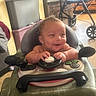 Armand is registered to the contest to win money with this photo: baby, child, infant, smiling, happy, face, portrait, indoor, activity_walker, toy, steering_wheel, seated, playtime, home, stroller, furniture, plastic, hands, bare_arms, candid