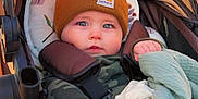 Bennett is registered to the contest to win money with this photo: baby, child, stroller, blanket, hat, beanie, clothing, face, hands, blue_eyes, camouflage, carhartt, infant, outdoor, warm_clothing, cute, seated, comfort, portrait, young_child