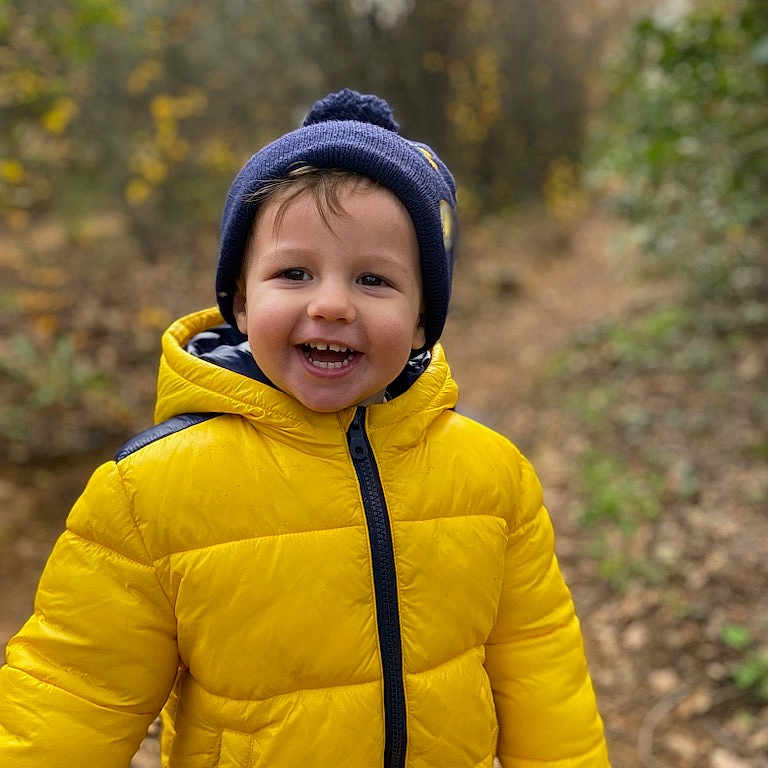 Aïdann participe au concours pour gagner de l'argent avec cette photo : baby, cap, clothing, coat, face, happy, hat, head, hood, hoodie, jacket, knitwear, person, photography, plant, portrait, smile, sweater, sweatshirt, vegetation