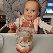 Noa participe au concours pour gagner de l'argent avec cette photo : baby, high_chair, bib, food, smile, happy, child, indoor, jar, dessert, tray, face, person, furniture, television, clothing, table, seat, cute, messy