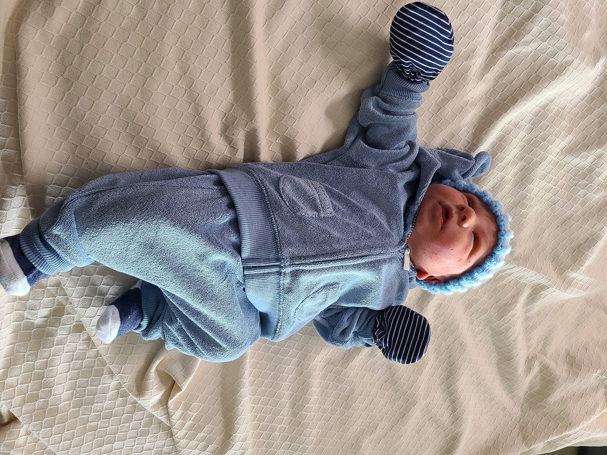 Nikolai is registered to the contest to win money with this photo: arm, baby, baby_toddler_clothing, child, comfort, denim, electric_blue, flooring, foot, gesture, grey, hand, headwear, human_leg, knee, linens, pattern, person, sitting, sleeve