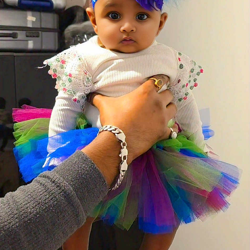 Aaira joined the competition — help win amazing prizes! accessory, adult, baby, child, clothing, colorful, curious, cute, fashion, feathers, hand, headband, holding, indoor, person, portrait, suitcase, tutu, wall, wide_eyes
