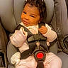 baby, car_seat, child, smiling, pink_pajamas, infant, face, seatbelt, strapped_in, cute, indoors, winking, headrest, clothing, person, safety_harness, dove_graphic, text_overlay, happy, portrait
