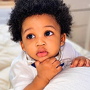 Jaydee is registered to the contest to win money with this photo: baby, child, closeup, curly_hair, cute, expression, eyes, face, hand, indoor, infant, pillow, portrait, resting, skin, soft_texture, thoughtful, toddler, white_clothing, young_child