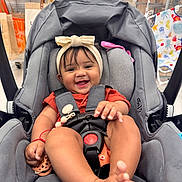 Valentina is registered to the contest to win money with this photo: baby, car_seat, smile, headband, infant, child, happy, indoor, shopping, store, toy, seat_belt, foot, hand, clothing, person, cute, playful, accessory, fabric