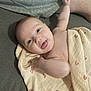 baby, infant, blanket, rainbow_pattern, tongue_out, arm, couch, fabric, person, skin, happy, smile, lying_down, closeup, human, cute, soft_texture, indoor, relaxed, parent