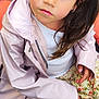 casual_clothing, child, cobblestone, curious, daylight, expression, face, floral_skirt, girl, outdoor, pigtails, pink, portrait, raincoat, sitting, sneakers, street, toy_vehicle, white_tights, young_child