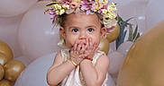 Nita is registered to the contest to win money with this photo: balloons, bracelet, celebration, child, cute, decorations, dress, face, festive, flower_crown, gold, hands, happy, indoor, party, portrait, smile, toddler, white, young_child