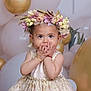 Nita is registered to the contest to win money with this photo: balloons, bracelet, celebration, child, cute, decorations, dress, face, festive, flower_crown, gold, hands, happy, indoor, party, portrait, smile, toddler, white, young_child