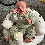 Alfie joined the competition — help win amazing prizes! baby, infant, knitted_clothing, sitting, smiling, happy, inflatable_chair, carpet, indoor, container, foot, hand, face, cute, child, young, cozy, playful, joyful, home