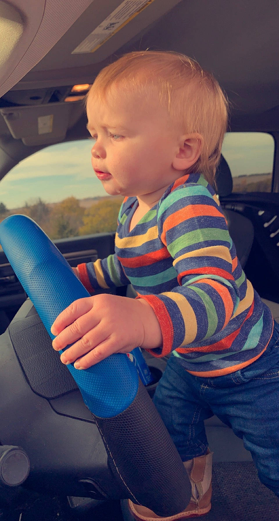 Connor John is registered to the contest to win money with this photo: auto_part, automotive_design, automotive_exterior, baby, baby_toddler_clothing, car, car_seat, car_seat_cover, child, finger, fun, gesture, human_body, person, product, skin, steering_wheel, thumb, toddler, vehicle